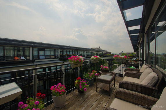 Rooftop view with outdoor seating and potted plants on a wooden deck.