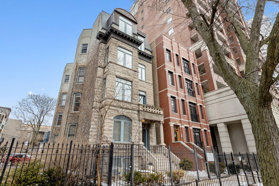 Front view of a multi-story stone and brick building with steps leading to the entrance.