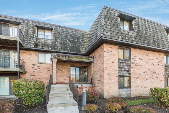 Front view of a multi-story brick building with wooden shingle siding.