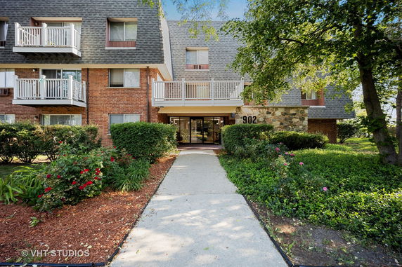 Front view of a multi-story residential building with balconies and numbered entrance.