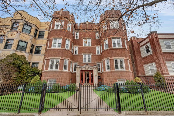 Front view of a multi-story brick building with a gated entrance