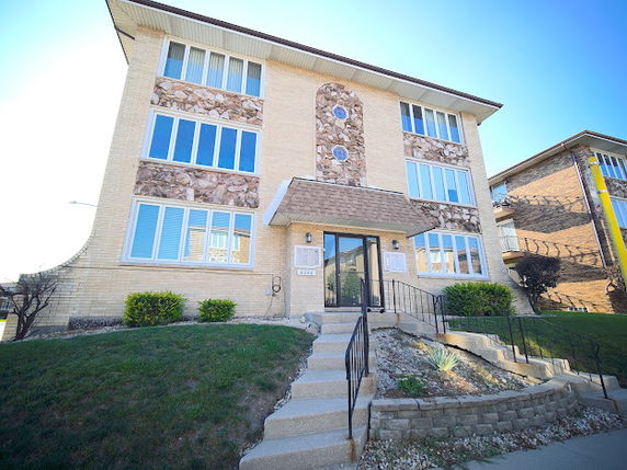 Front view of a multi-story residential building with large windows.