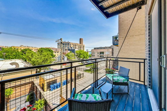 View from a balcony overlooking an urban landscape with buildings and trees.