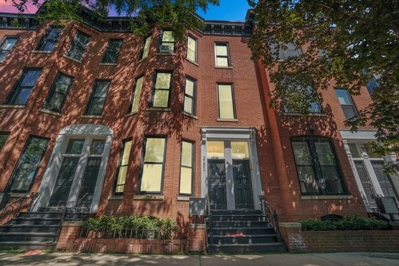 Front view of a multi-story brick row house with steps leading up to the entrance.