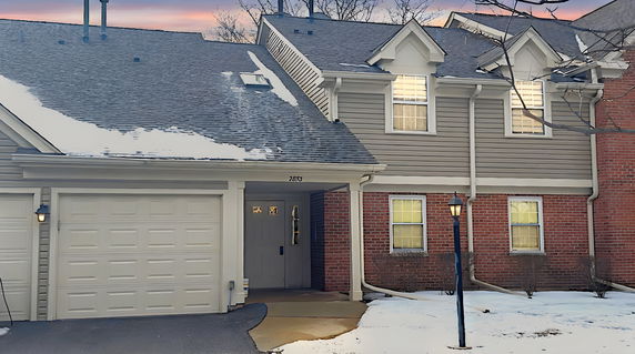 Front view of a townhouse with a garage and brick facade.