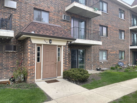 Front view of a brick apartment building with balconies and an entrance door.