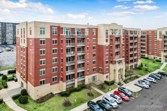 Front view of a multi-story brick apartment complex with balconies and parking area.