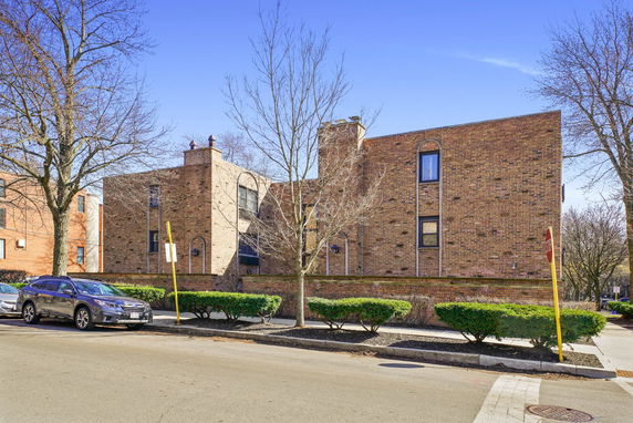 Front view of a two-story brick building with large windows and chimneys.