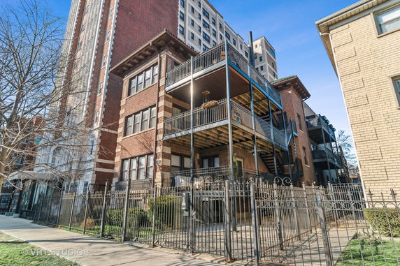 Front view of a multi-story brick apartment building with balconies.