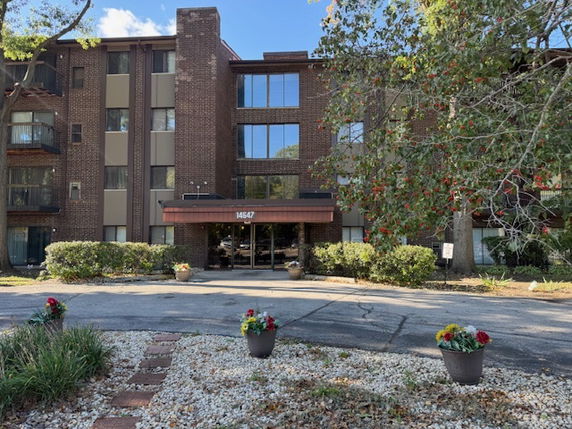Front view of a multi-story brick building entrance with large windows.