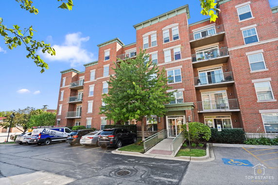 Front view of a multi-story brick apartment building with balconies.