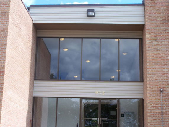 Front view of a building entrance with large glass windows and brick walls.