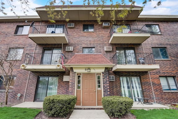 Front view of a brick apartment building with balconies and a central entrance.