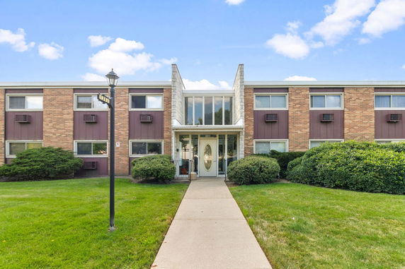 Front view of a two-story apartment building with brick facade and central entrance.