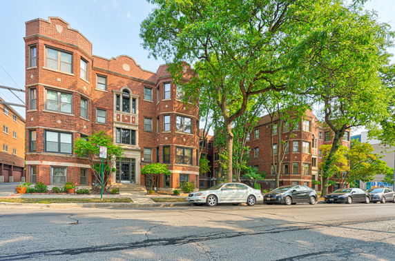 Front view of a multi-story brick apartment building with large windows.