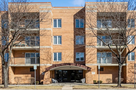 Front view of a multi-story brick apartment building with balconies.