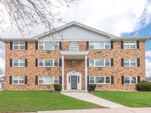 Front view of a three-story brick apartment building with symmetrical windows and a central entrance.