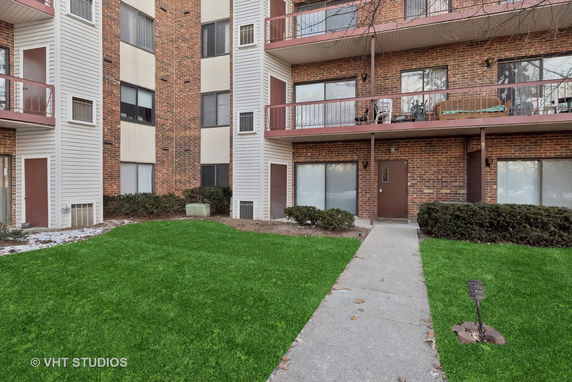 Front view of a multi-story brick apartment building with balconies.