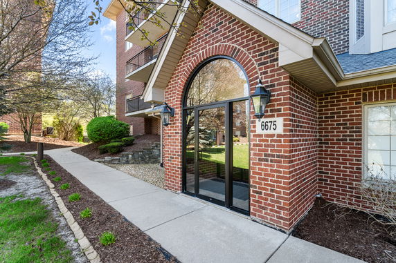 Front view of a brick building entryway with a glass door and arched window.