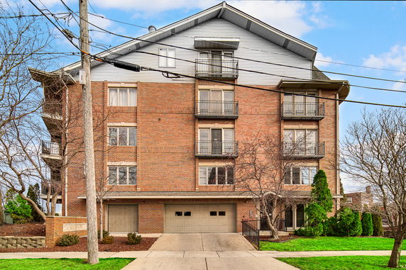 Front view of a multi-story brick apartment building with balconies and a garage.