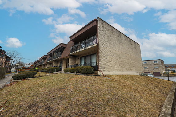 Front view of a multi-story residential building with brick exterior and balconies.