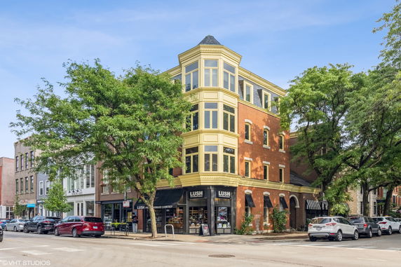 Front view of a multi-story brick building with large windows.