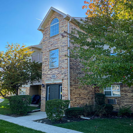 Front view of a multi-story brick townhouse with large windows.