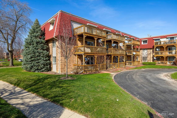 Front view of a multi-story building with wooden balconies and red roofing.