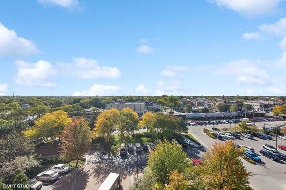 Panoramic view of a town with parking lot, buildings, and trees.