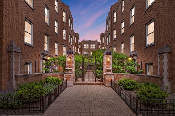 Front view of a multi-story brick building with a gated entrance.