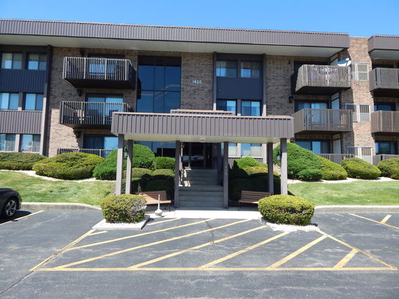 Front view of a multi-story apartment building with balconies and a covered entrance.