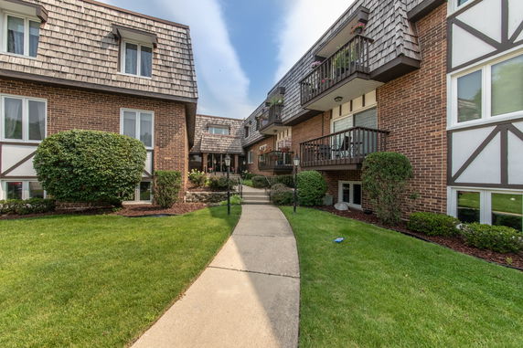 Front view of a multi-story residential building with brick facade and balconies.