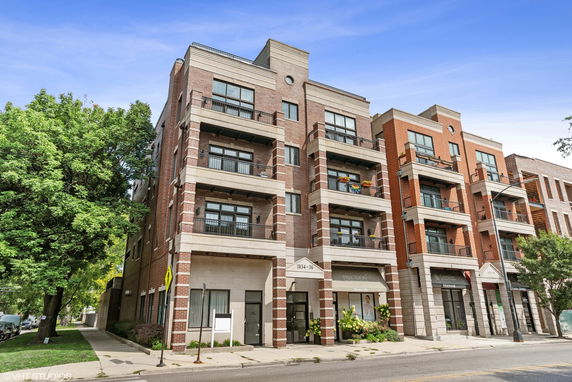 Front view of a multi-story brick apartment building with balconies.