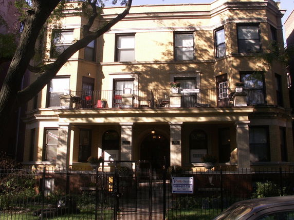 Front view of a three-story brick apartment building with balconies.