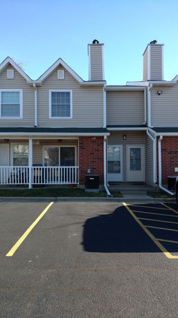 Front view of a townhouse with two stories and a porch.