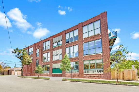Front view of a multi-story brick building with large windows.