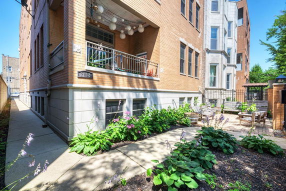 Corner view of a multi-story residential building with a balcony and patio area.