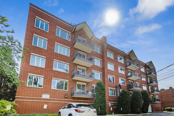 Front view of a multi-story brick apartment building with balconies.