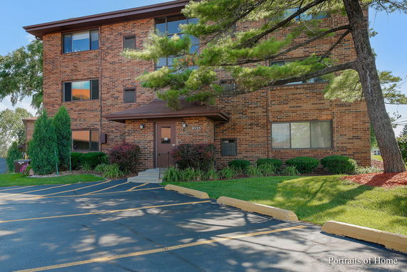 Front view of a multi-story brick building with a paved parking area.