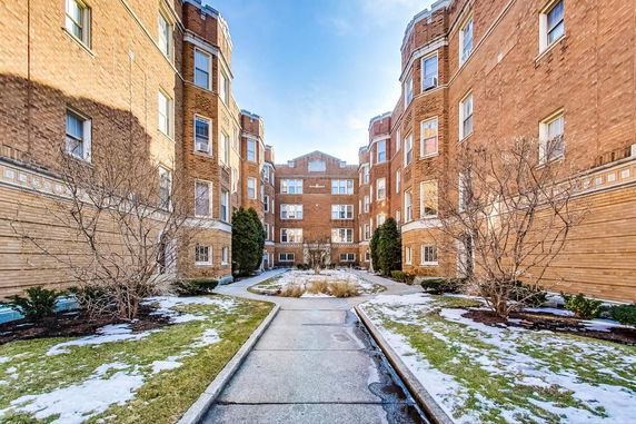 Front view of a multi-story brick building with an entrance courtyard.