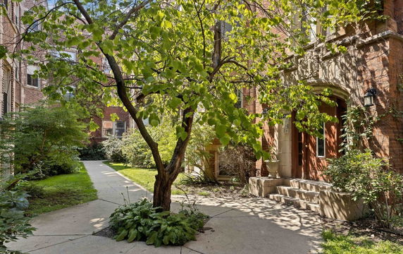 Front view of a building entrance with stairs and decorative stonework around the door.