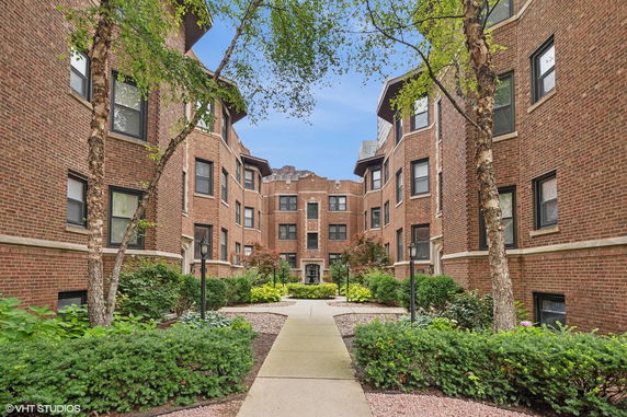 Front view of a brick apartment building with courtyard.