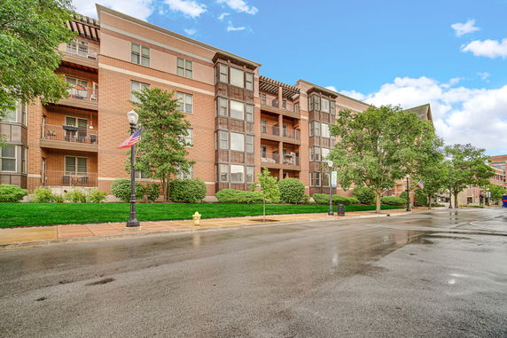 Front view of a multi-story residential building with red brick exterior and balconies.