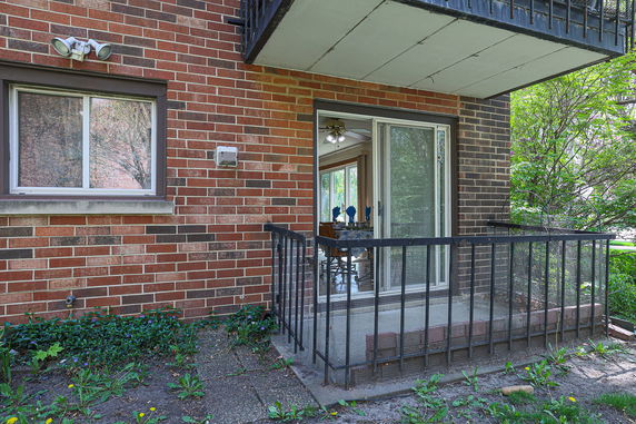 Exterior corner view of a brick building with a railing-enclosed patio.
