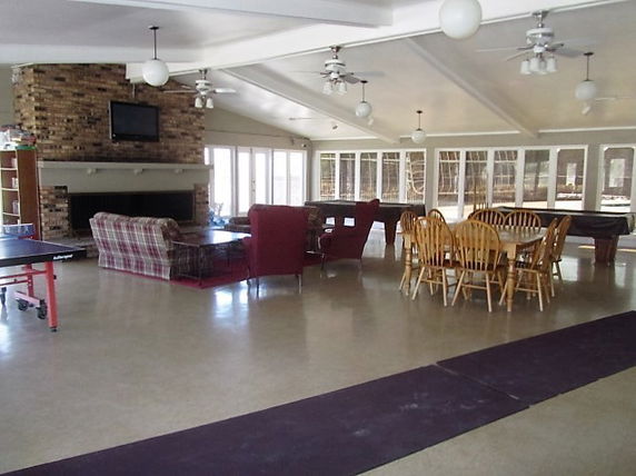 Indoor recreational area with seating, dining tables, and fireplace.