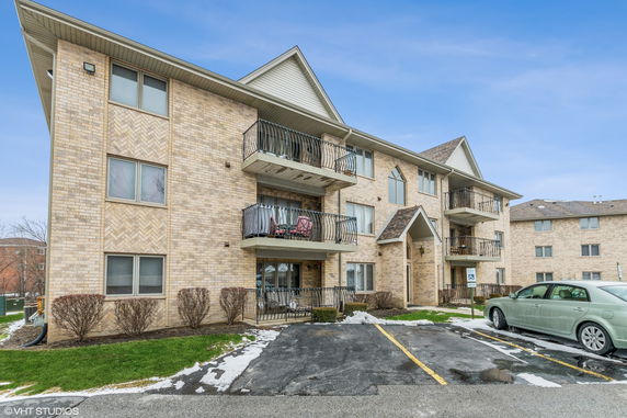 Front view of a multi-story apartment building with balconies and brick exterior.