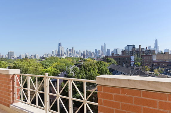 Panoramic view of a city skyline from a rooftop with a railing.