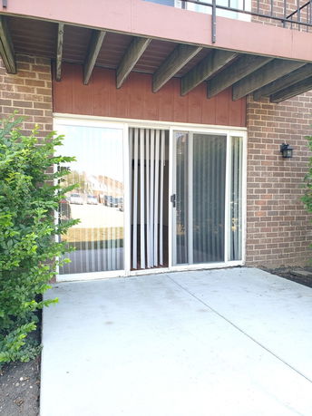 Front view of a brick house with sliding glass doors and a small concrete patio.