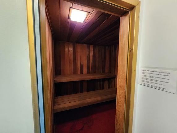 Interior view of a small wooden sauna room with benches.