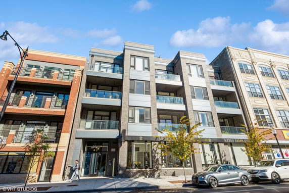 Front view of a modern multi-story building with balconies and large windows.